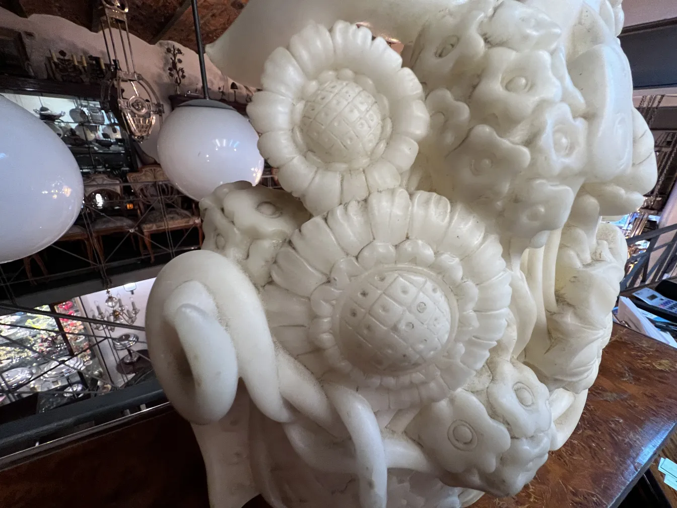 Antique sculpture with intricate floral details, white and elaborate in an antique setting.