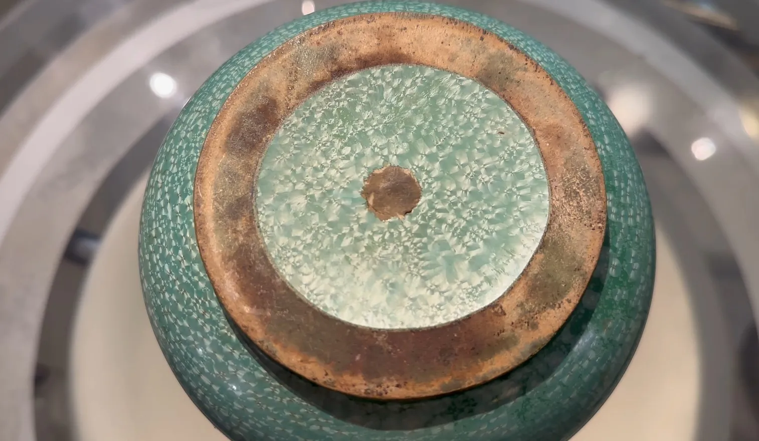 Base di ceramica antica in tonalità verdi con texture distintiva, in un ambiente minimalista.