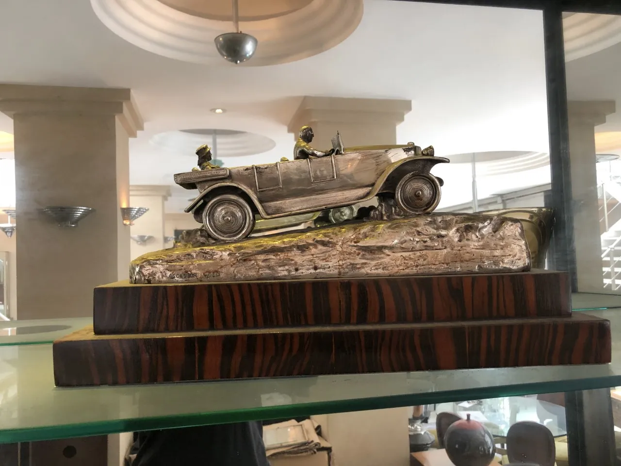 Escultura antiga de um carro decorativo em uma base.