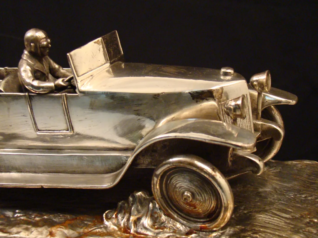 Antique sculpture of a car with a driver, shiny detail