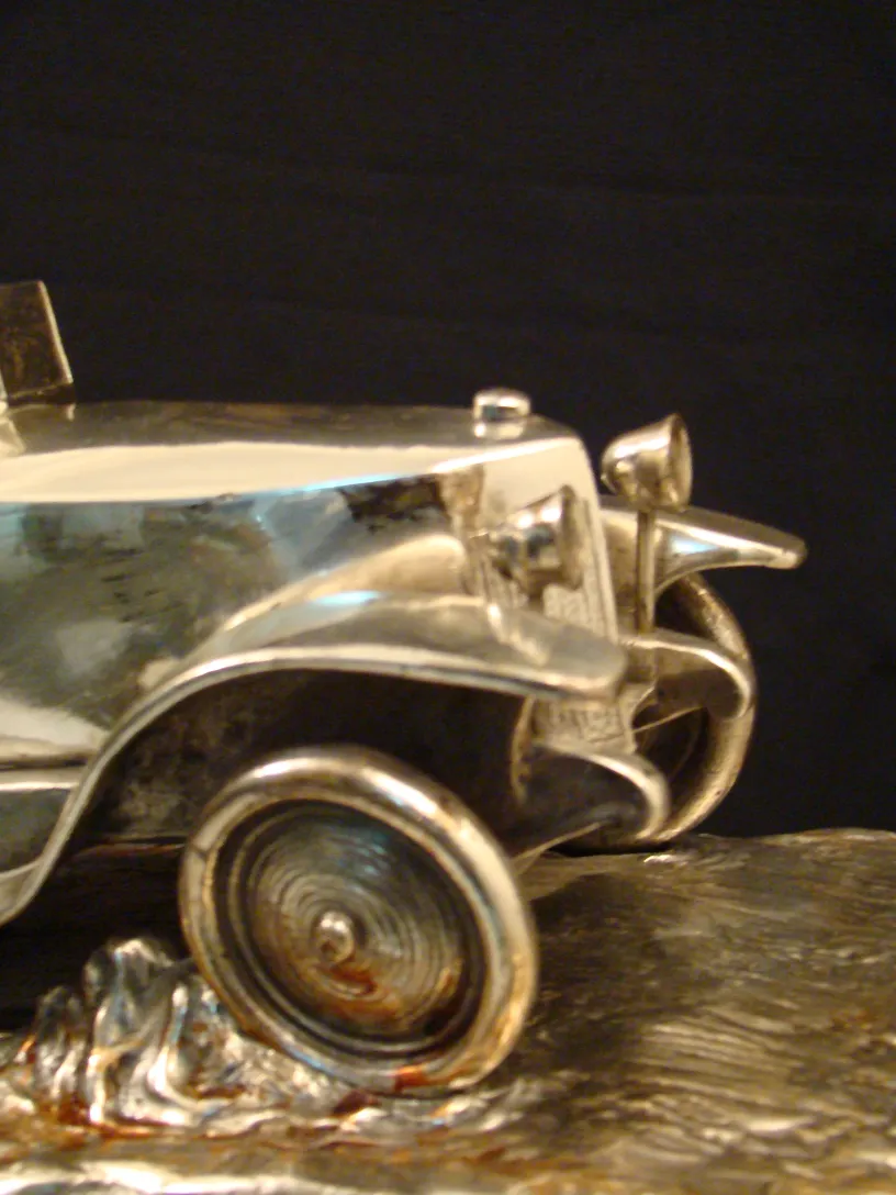 Antique sculpture of a shiny miniature car with details.