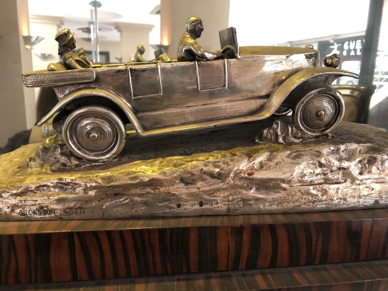 Antike Skulptur eines Autos mit sitzenden Figuren.