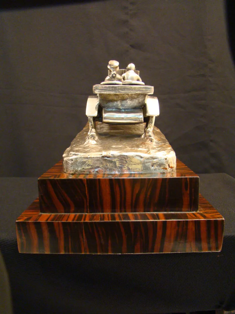 Antique sculpture featuring figures on a wooden base.