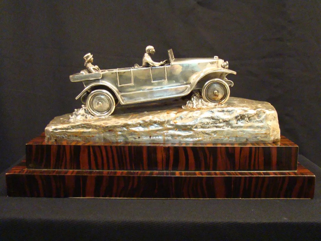 antique sculpture of a car with two figures inside