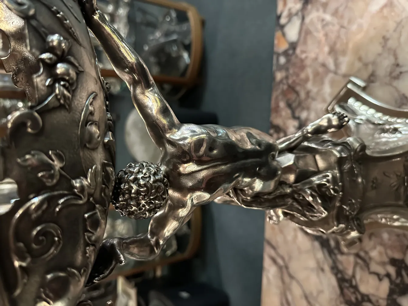 Escultura antiga com detalhes ornamentais em metal, figura masculina em ação