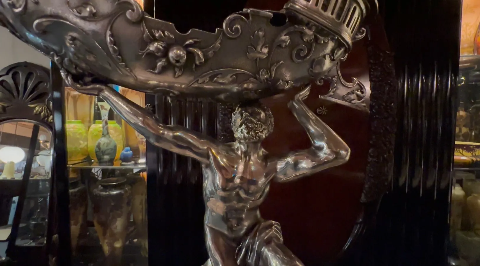 scultura antica di un uomo che solleva una lampada decorativa