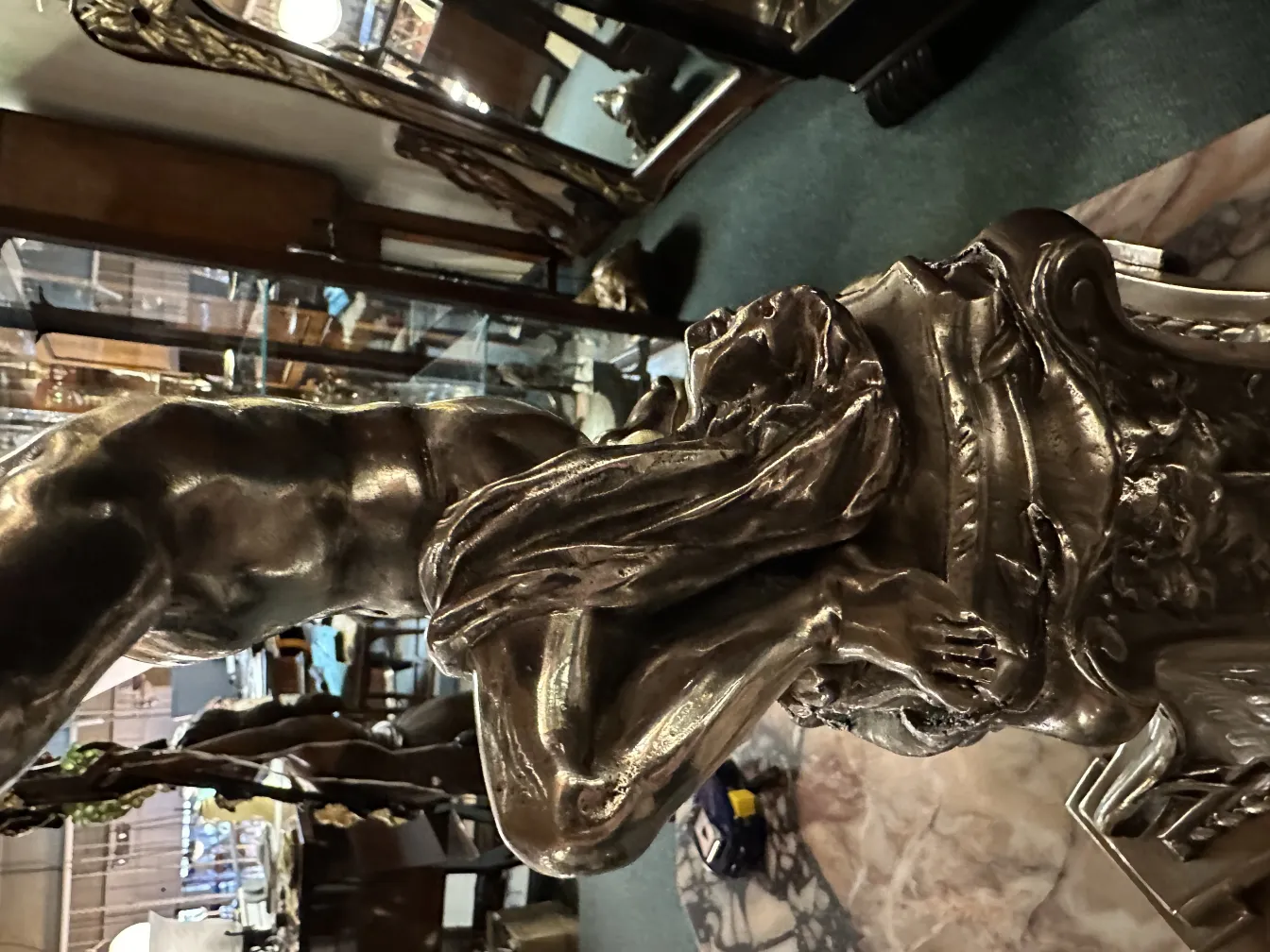 Antike Skulptur mit detaillierter Figur und verziertem Sockel.