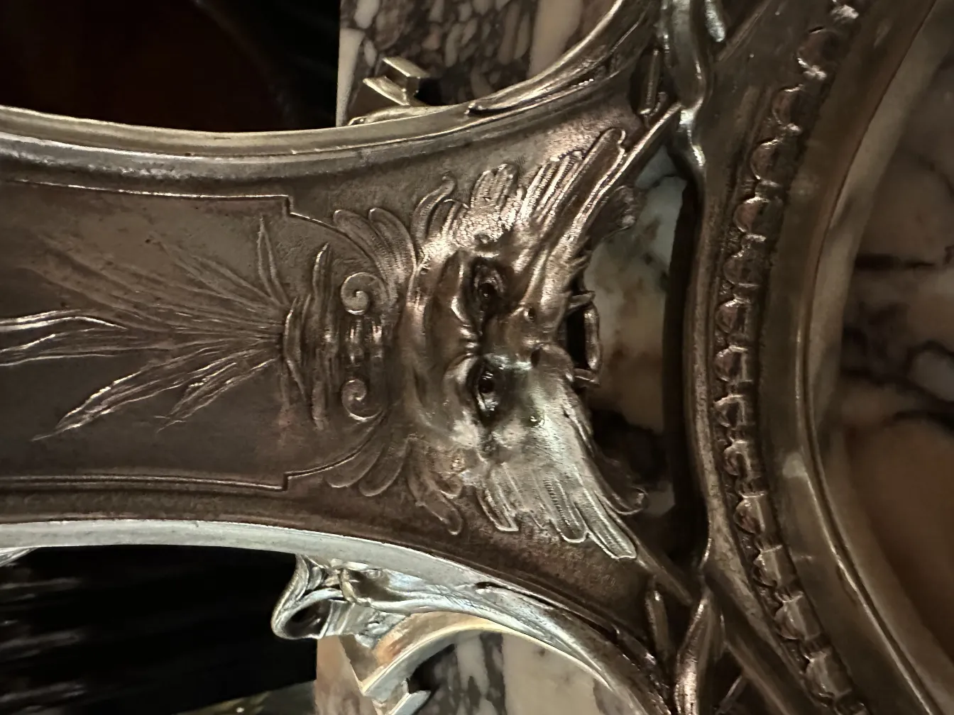 Escultura antiga em relevo com detalhes faciais, fundo escuro.