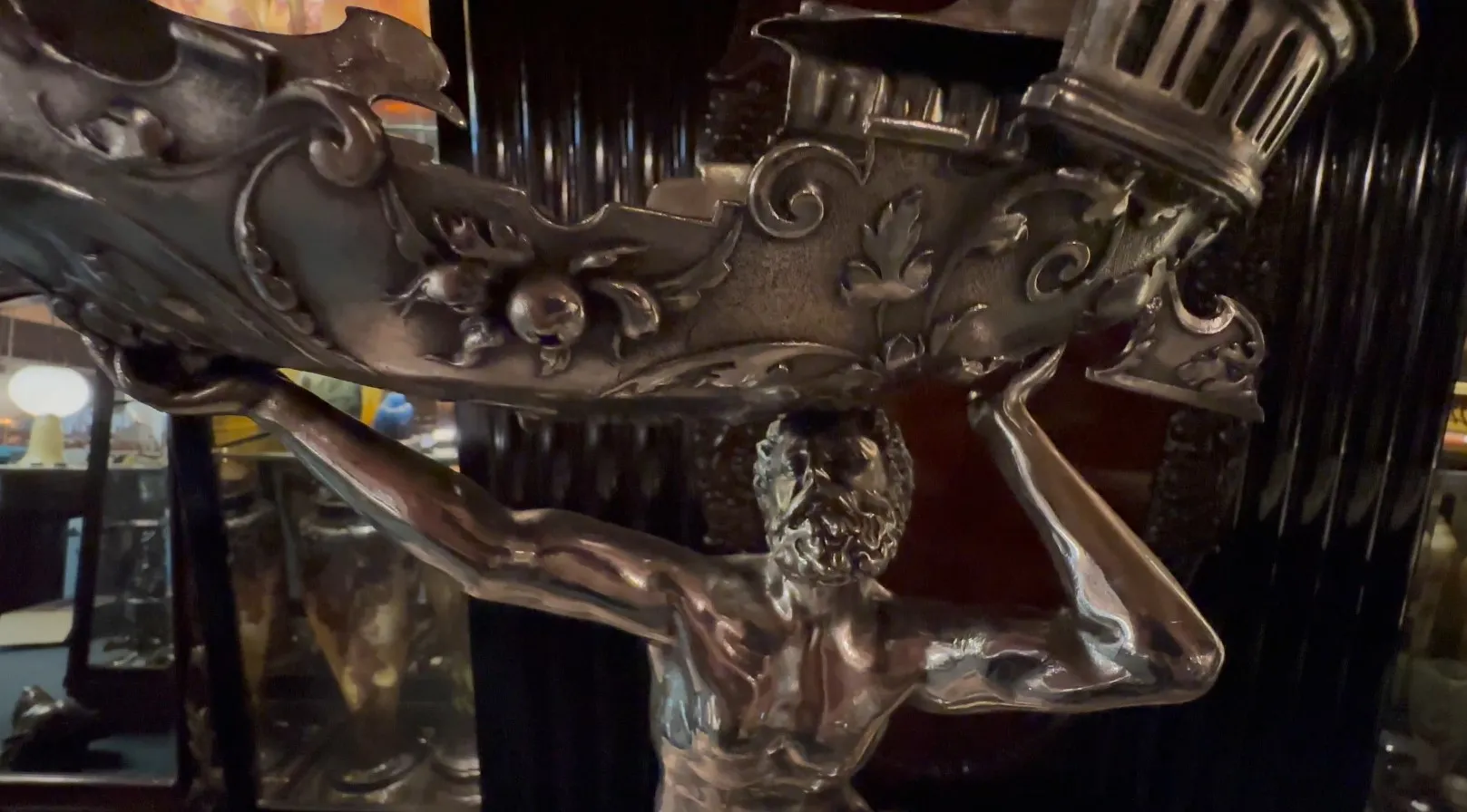 antike Skulptur mit männlicher Figur, die eine aufwendige Basis hält