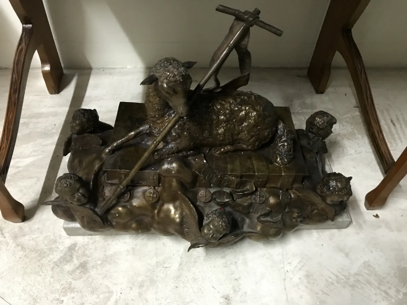 Antique sculpture depicting a sheep with children adoring, golden details, classic style.