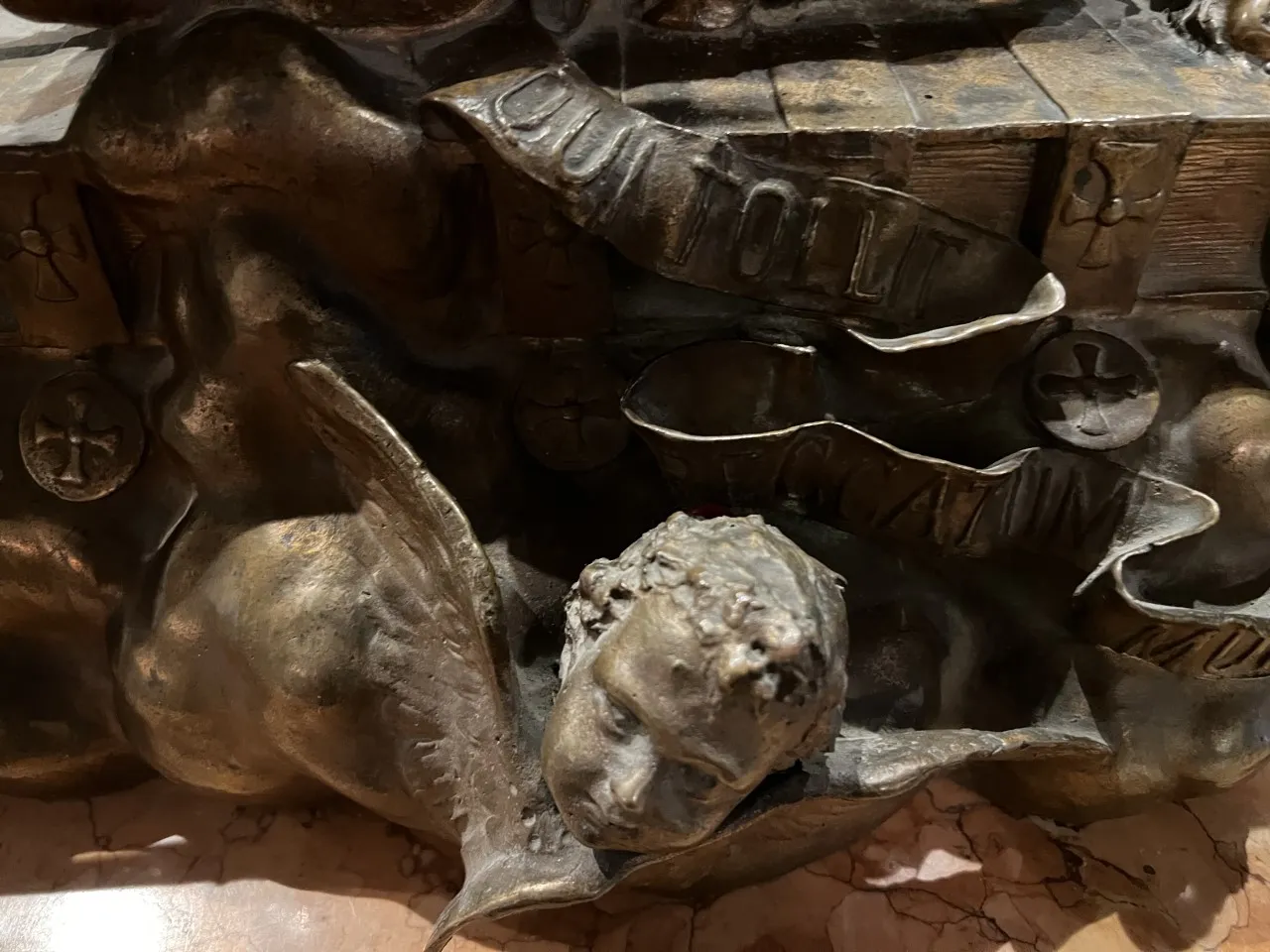 Escultura antigua de un ángel con rostro sereno y alas desplegadas.