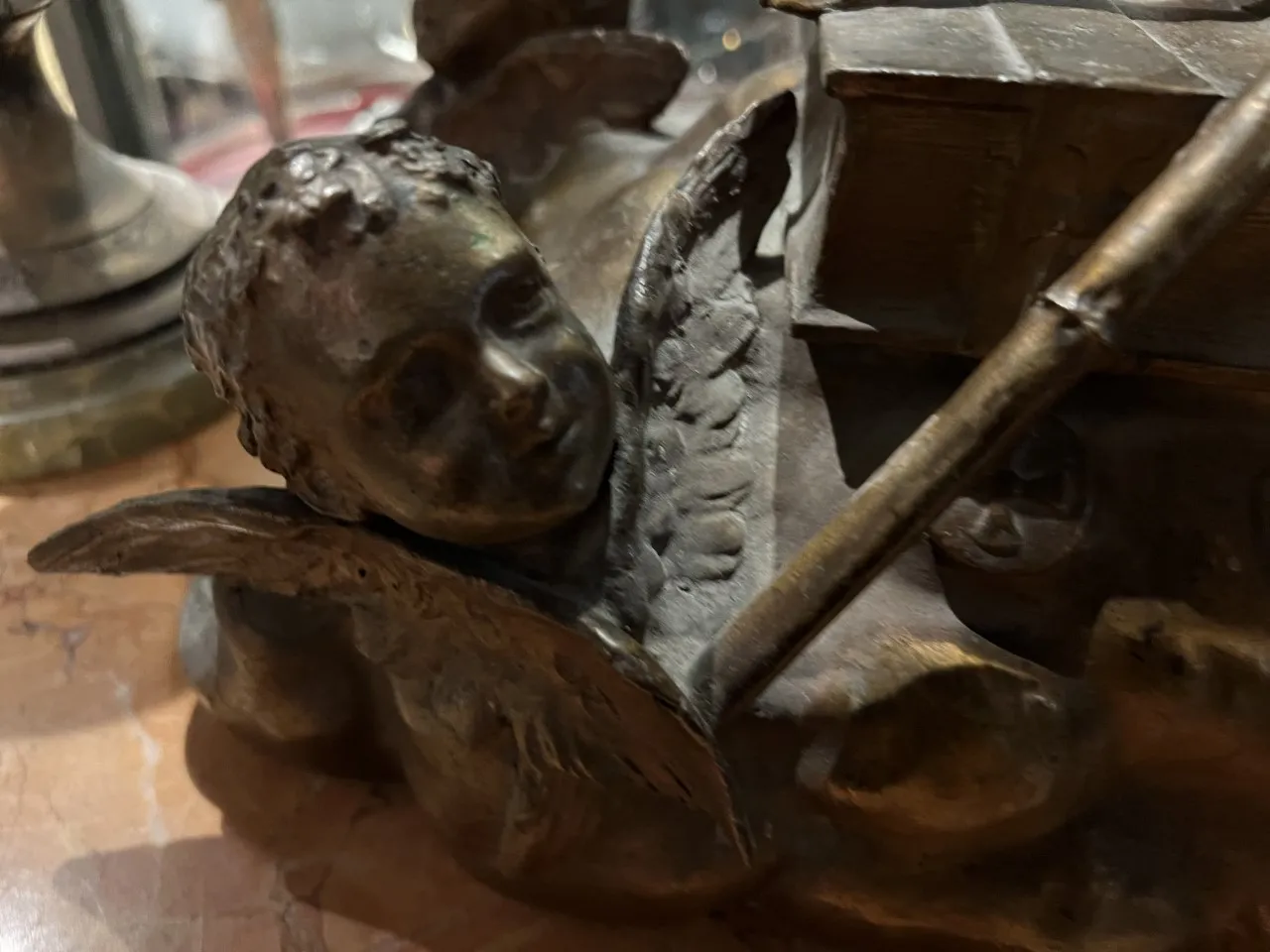 scultura antica di un angelo con espressione serena, circondata da dettagli ornamentali