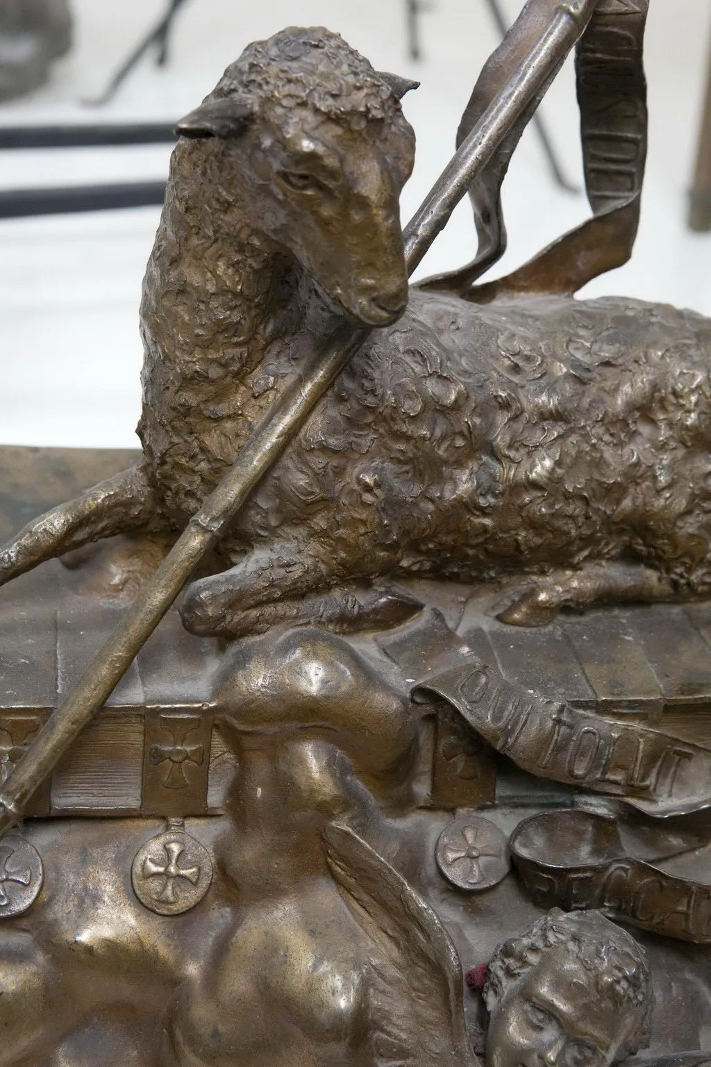 Escultura antigua de oveja con figuras mitológicas distintivas