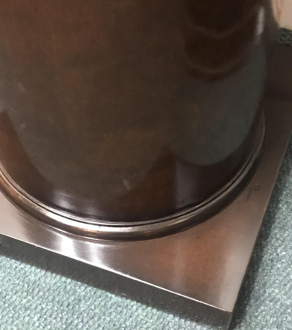 Antike Säule mit Metallbasis in klassischer Umgebung.