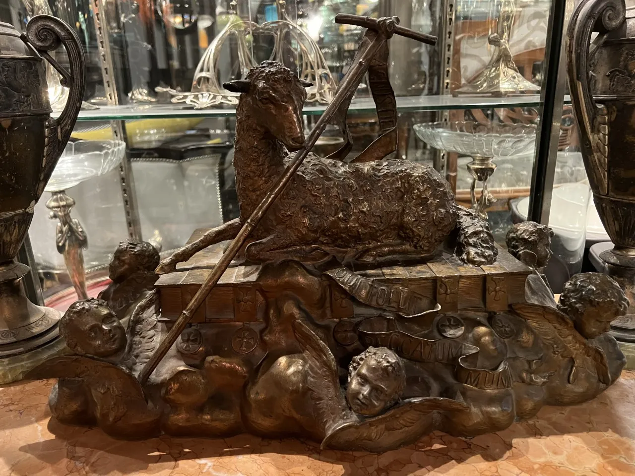 Sculpture ancienne montrant un agneau et des chérubins dans un cadre élégant