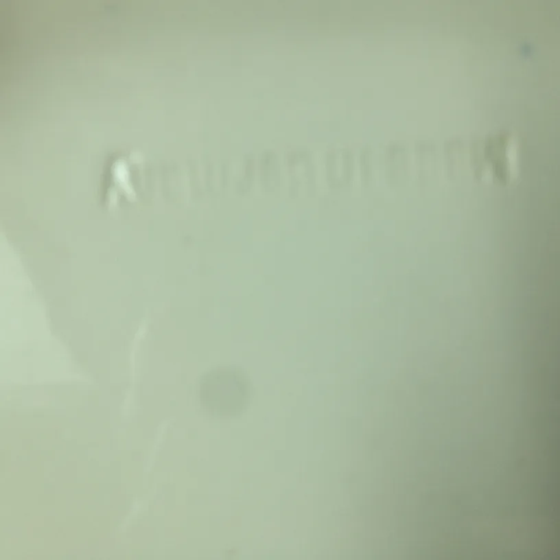 Cerâmica antiga com selo visível e leve inscrição. Fundo claro.