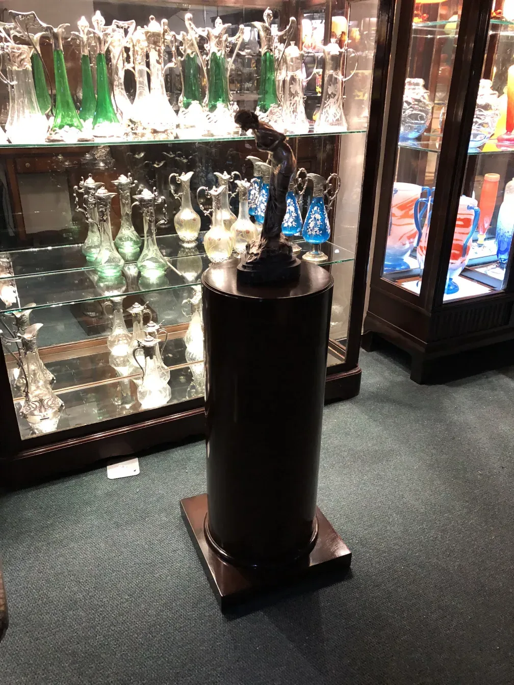 Schwarze antike dekorative Säule mit einer Figur an der Basis.