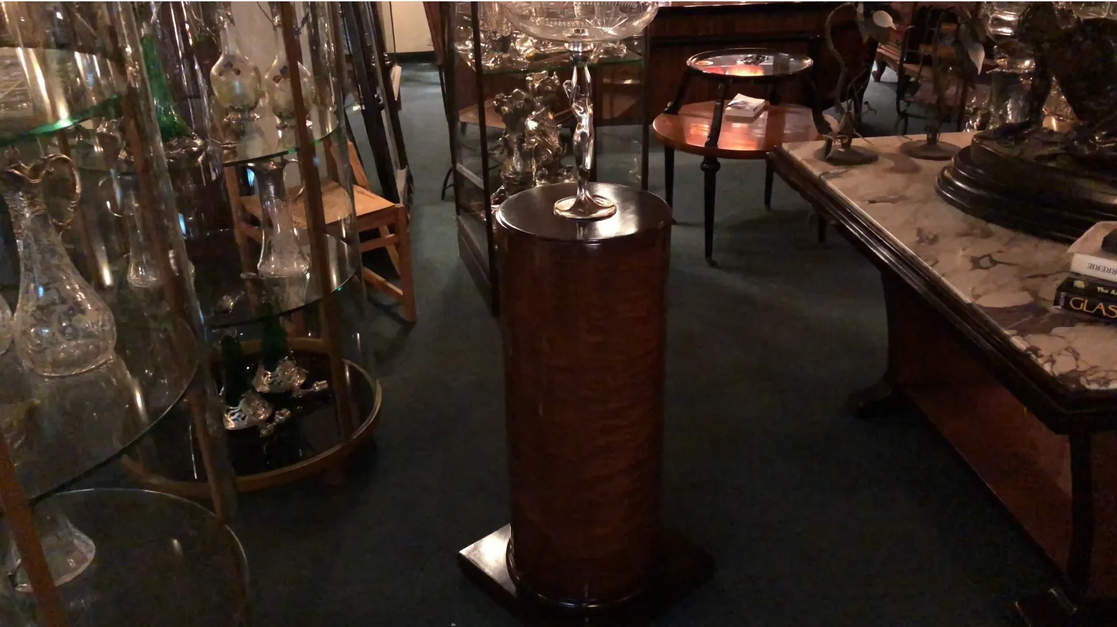 Decorative antique column with a wide base and intricate details, surrounded by antiques.