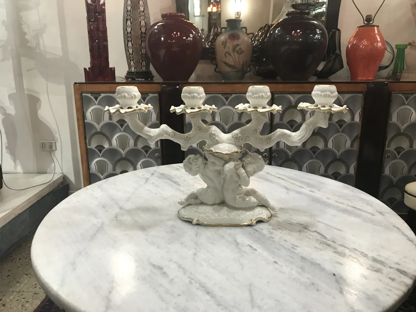 Candelabro de cerâmica antiga com querubins em um ambiente clássico.