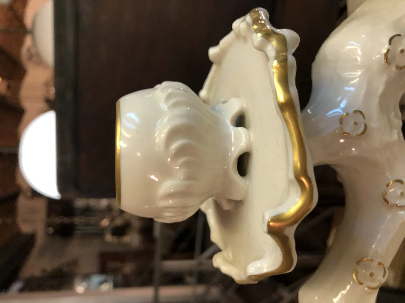 Détails d'une ancienne pièce en céramique blanche avec des accents dorés, mettant en valeur son ornements et son style décoratif dans un cadre classique.