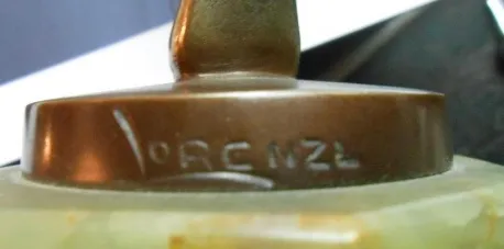 Antike Skulptur mit sichtbarer Signatur an der Basis, in einem dekorativen Umfeld.