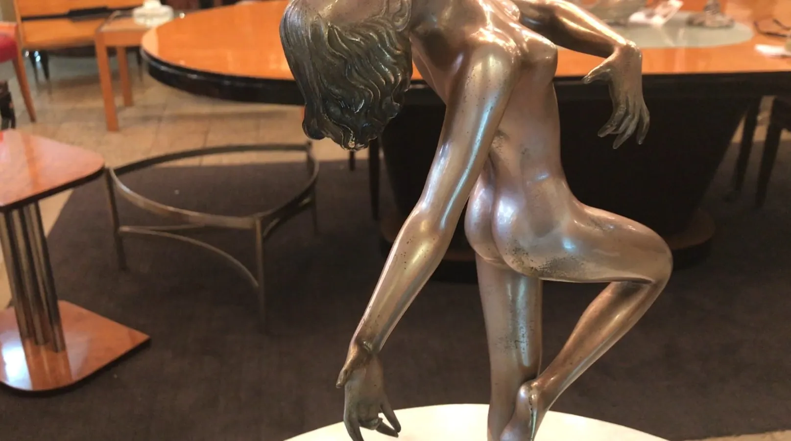 Sculpture ancienne d'une figure en pose délicate, fond avec une table