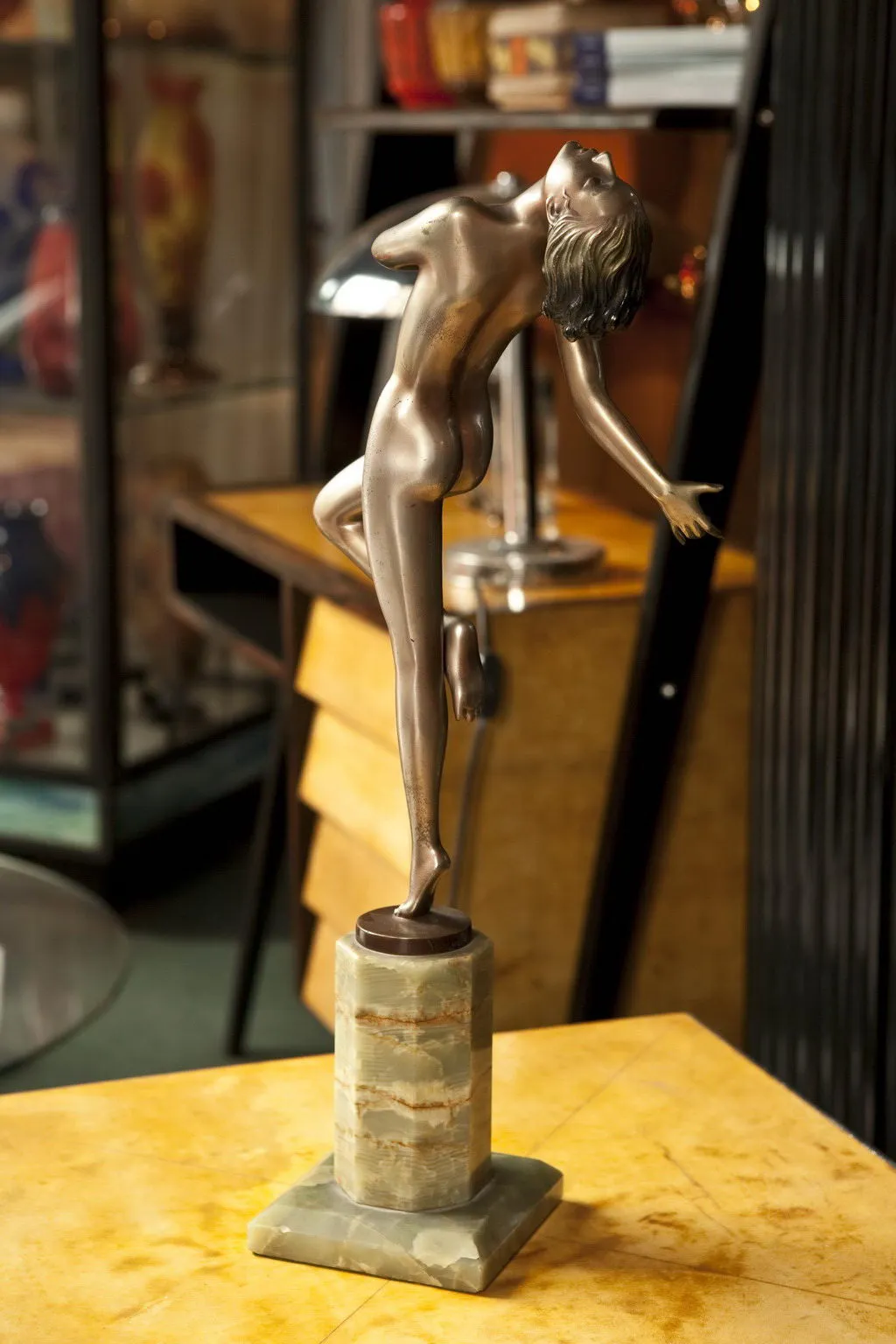 Scultura antica di una figura danzante su un piedistallo.