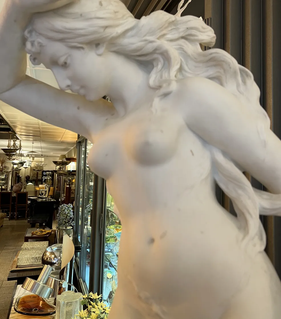 escultura antigua de mujer con cabello ondulado, en un entorno elegante