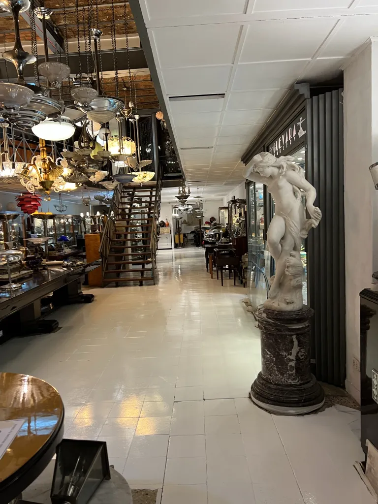 escultura antiga em pedestal com objetos decorativos