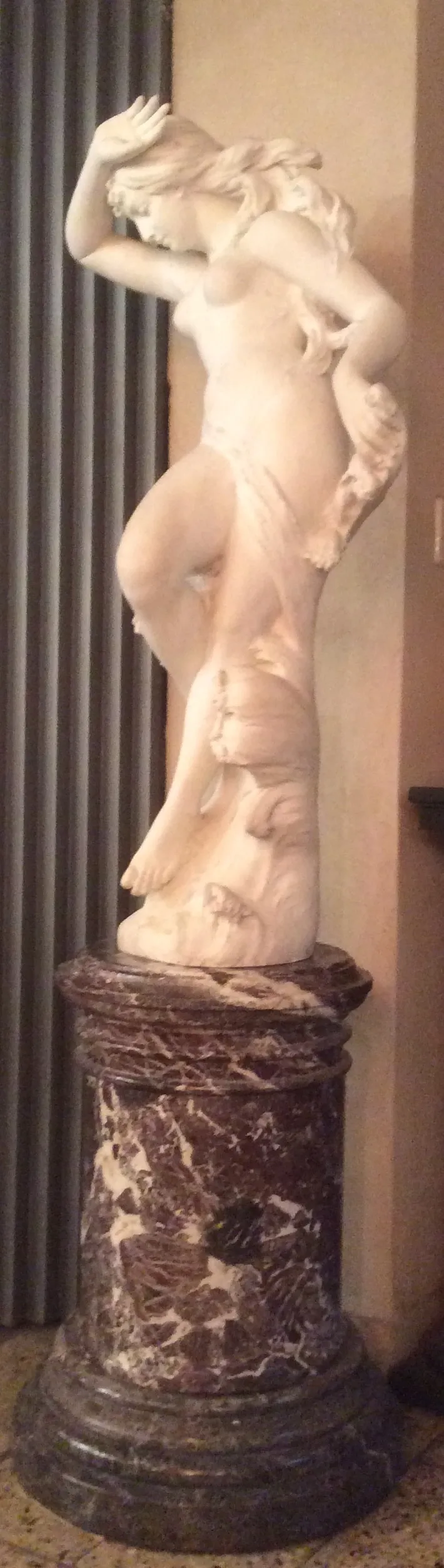 sculpture antique présentant une figure féminine sur un piédestal détaillé