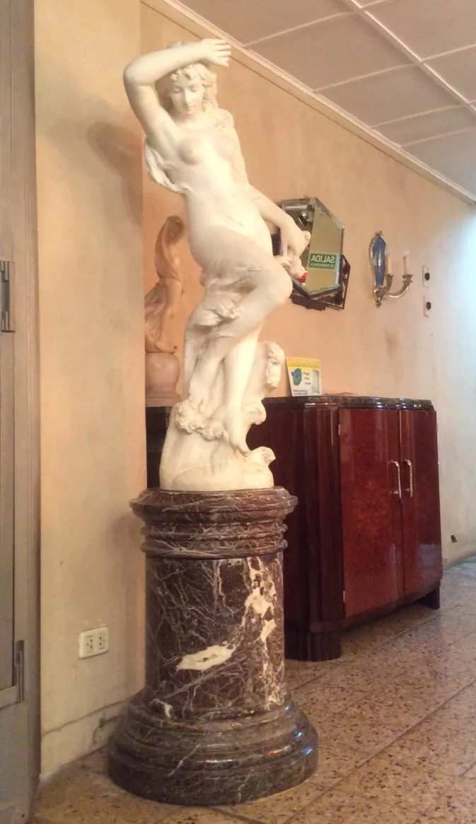 sculpture ancienne de femme avec des détails et un piédestal dans un salon