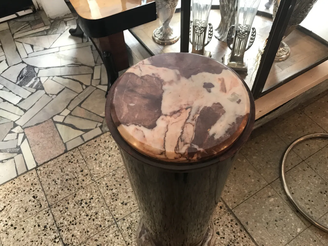 colonne ancienne avec sommet décoratif et base ronde, arrière-plan avec d'autres objets