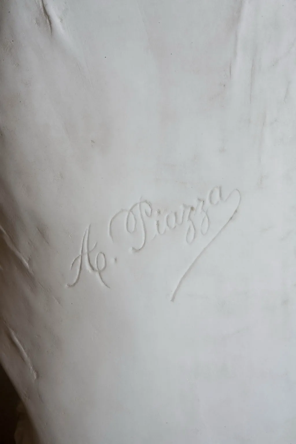 Escultura antiga com a assinatura de A. Piazza, exibindo uma tonalidade branca e texturas suaves.