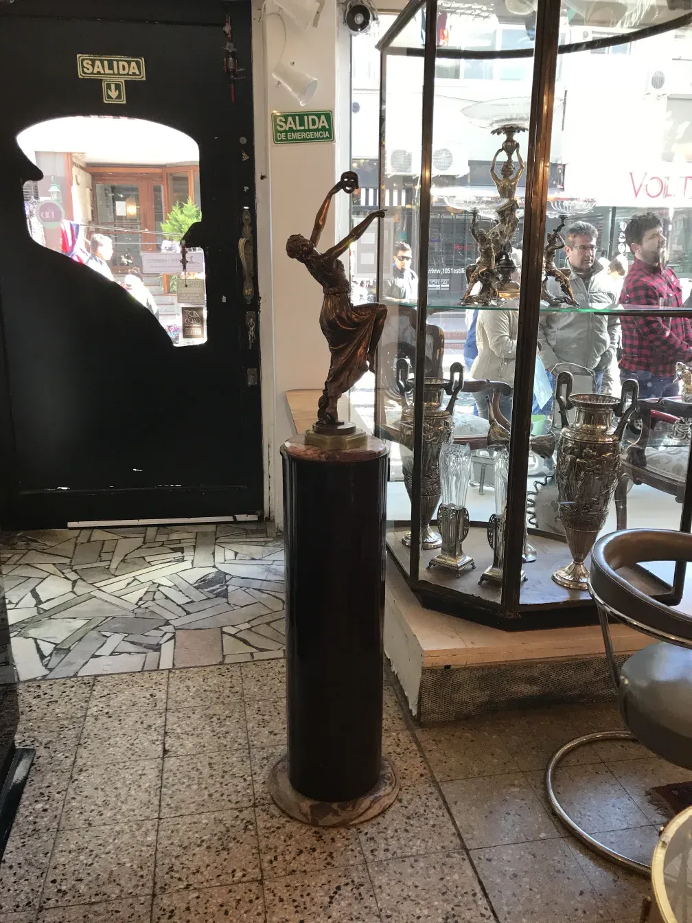 antike Säule mit dekorativer Figur oben und Hintergrund des Geschäfts.