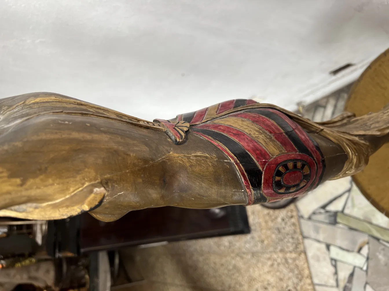 escultura antiga com detalhes decorativos em vermelho e dourado, em um ambiente clássico