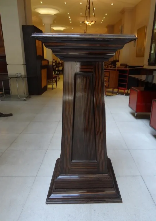 Coluna antiga decorativa com detalhes estilizados em um ambiente elegante.