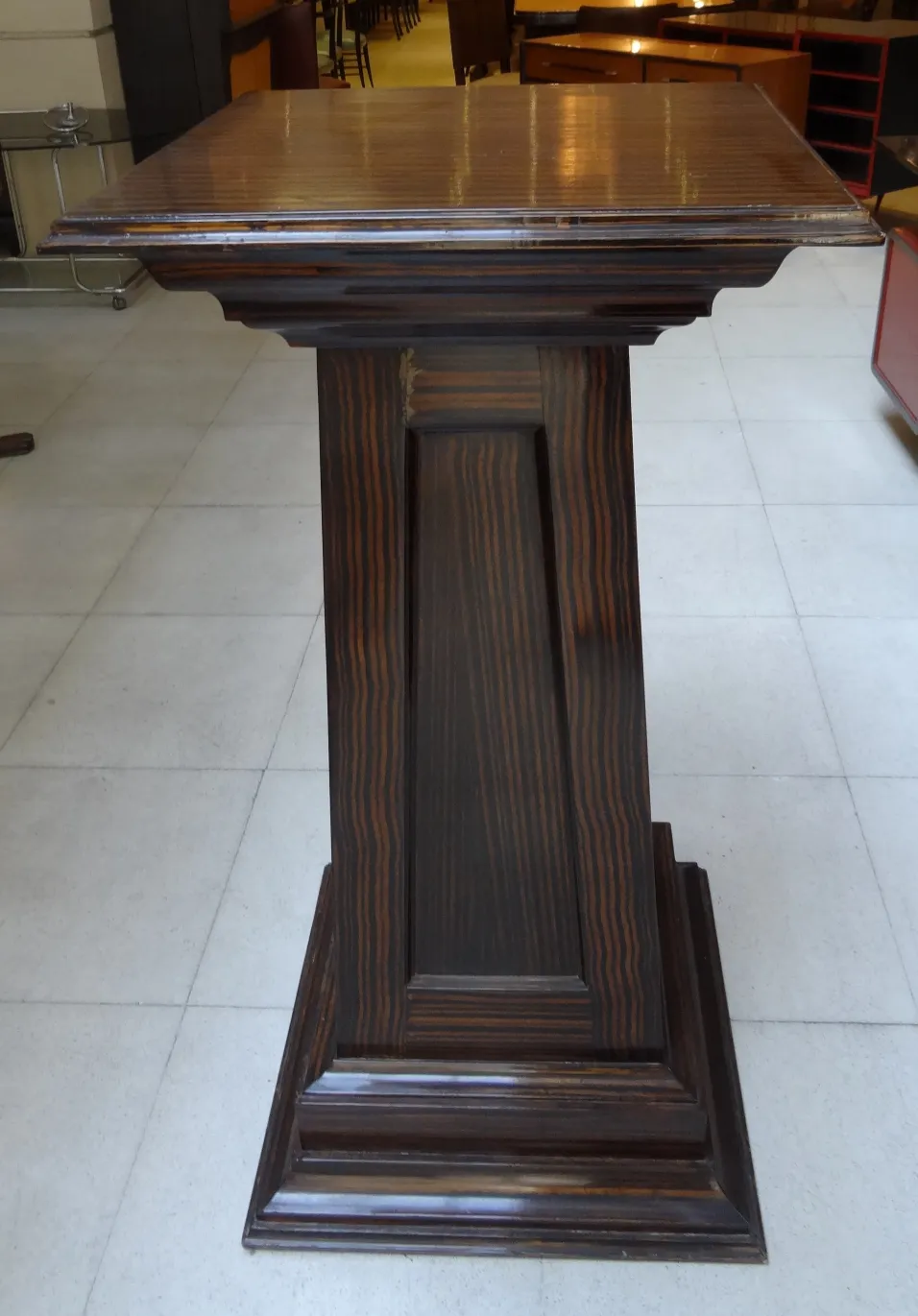 columna antigua con detalle en la parte superior, fondo con muebles