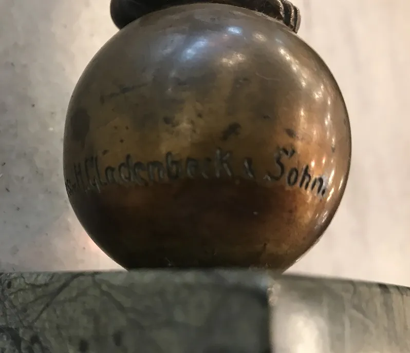 Antike Skulptur mit detaillierter Basis und hellem Hintergrund.