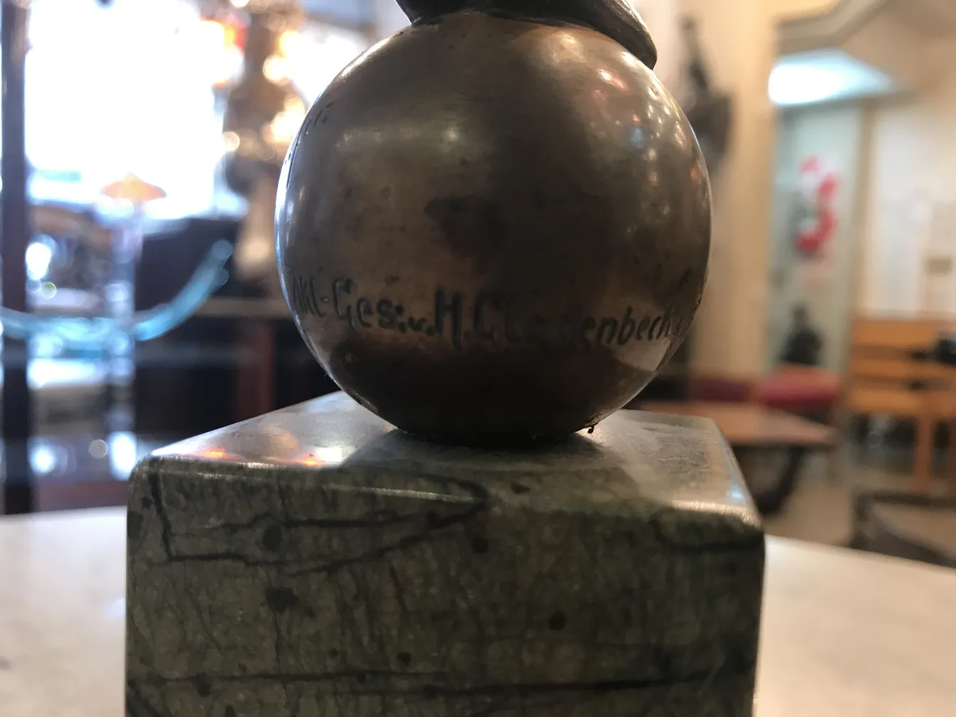 escultura antigua con forma esférica y base cuadrada en un ambiente de museo