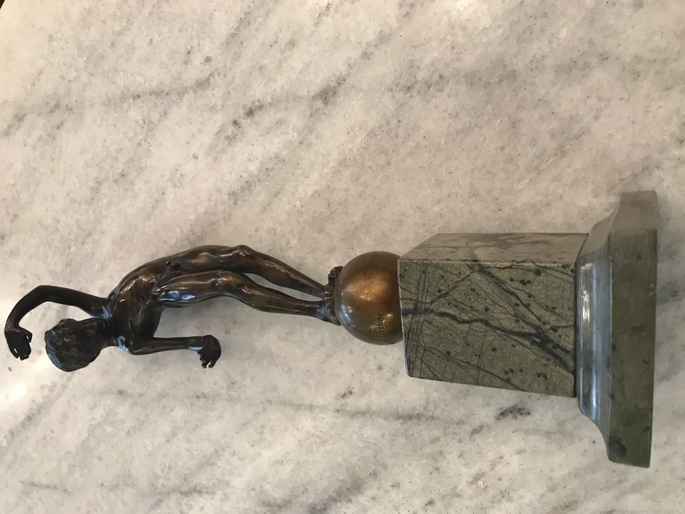 Antique sculpture of a human figure in motion on a base