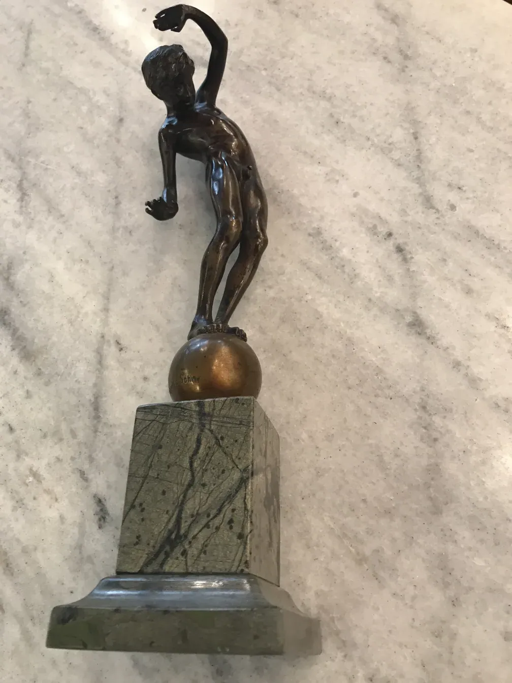 escultura antiga de figura masculina em pose dinâmica sobre pedestal