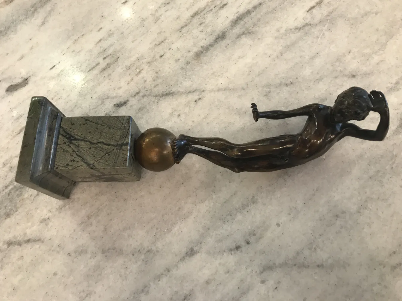 escultura antigua de un hombre en posición relajada sobre base