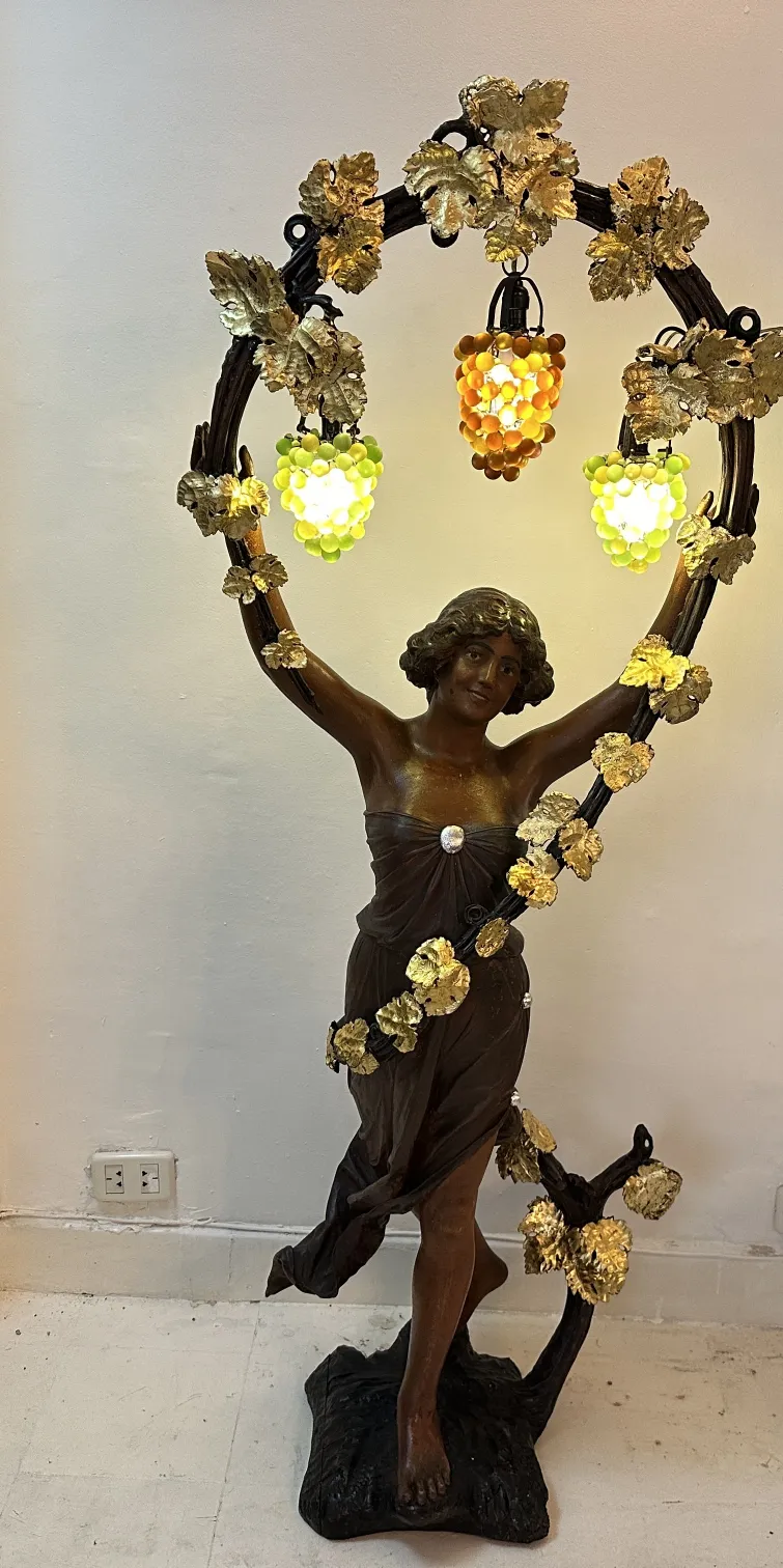 escultura antigua de mujer sosteniendo luces decorativas en un entorno elegante