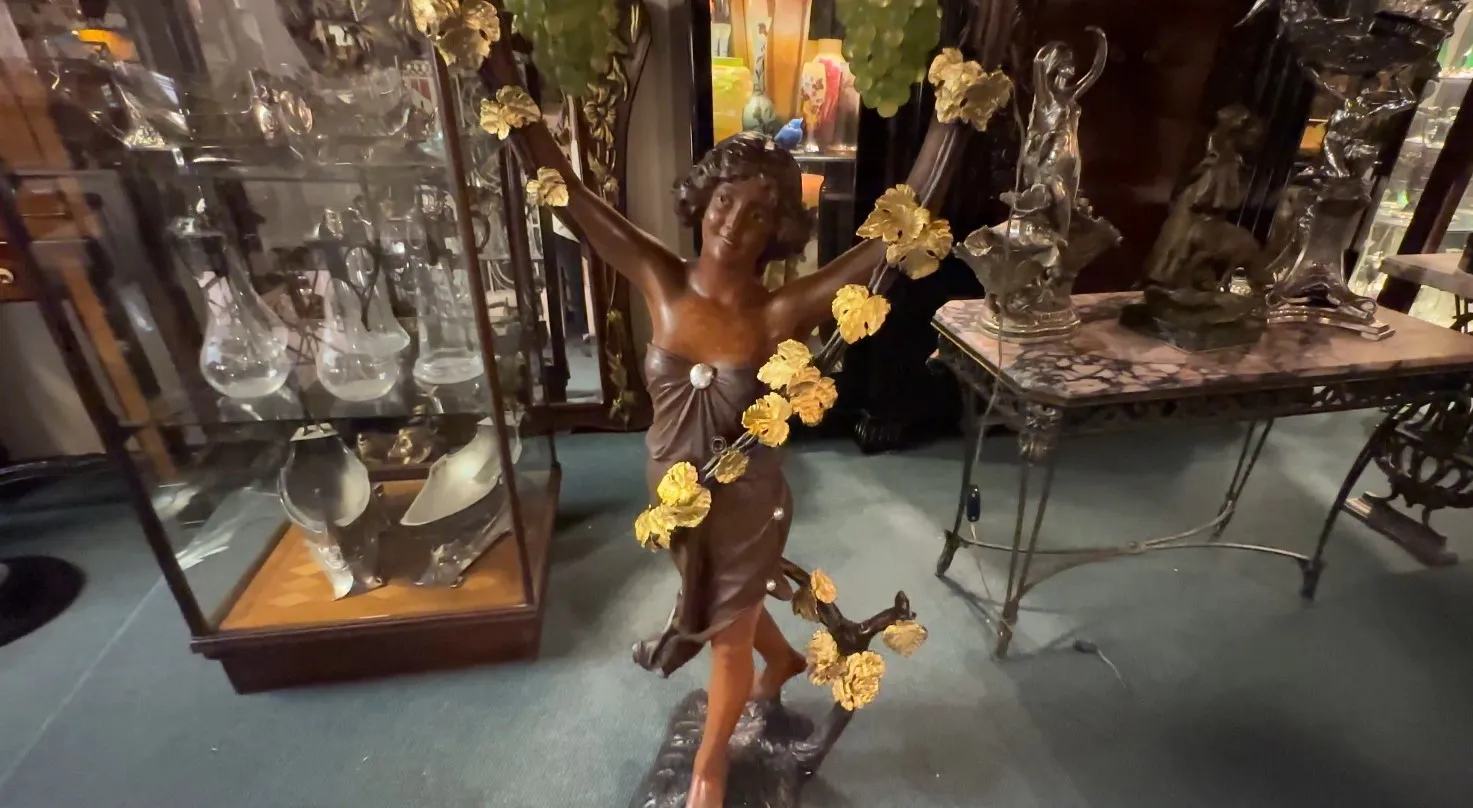 escultura antiga de mulher cercada por folhas douradas em ambiente clássico