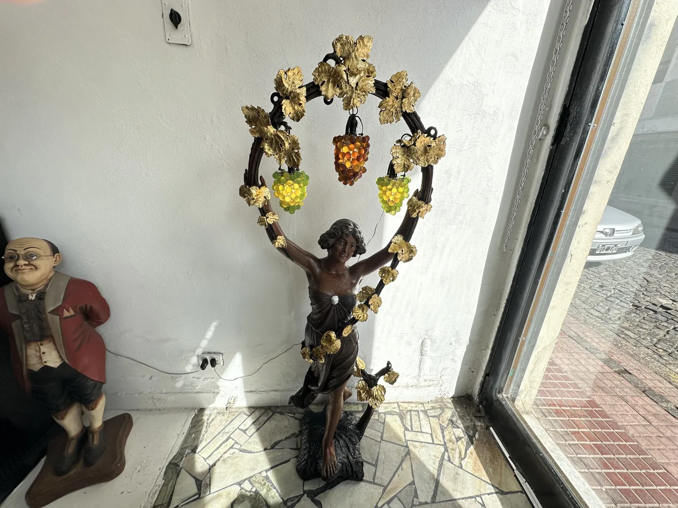 Sculpture antique d'une figure avec des raisins et des feuilles décoratives.