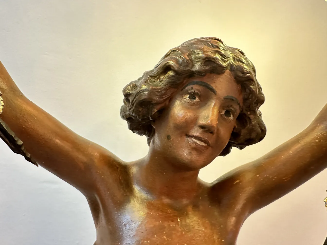 Antike Skulptur, die eine lächelnde menschliche Figur darstellt, mit detaillierten Haaren.