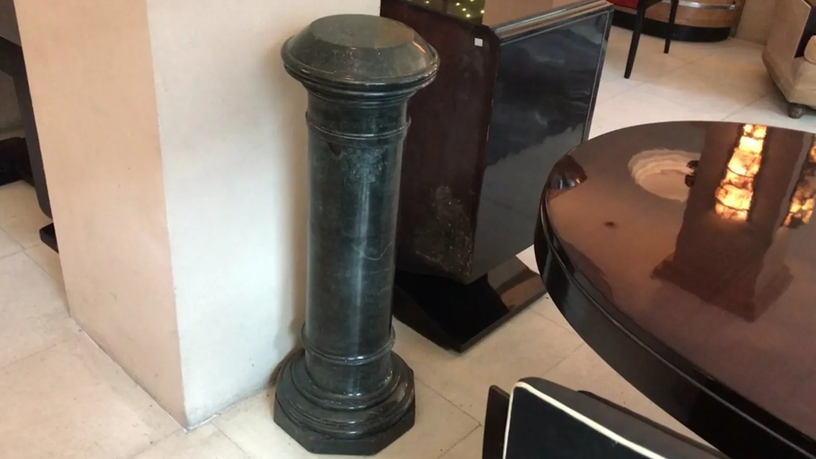 Colonne décorative antique dans une pièce avec des meubles en arrière-plan.