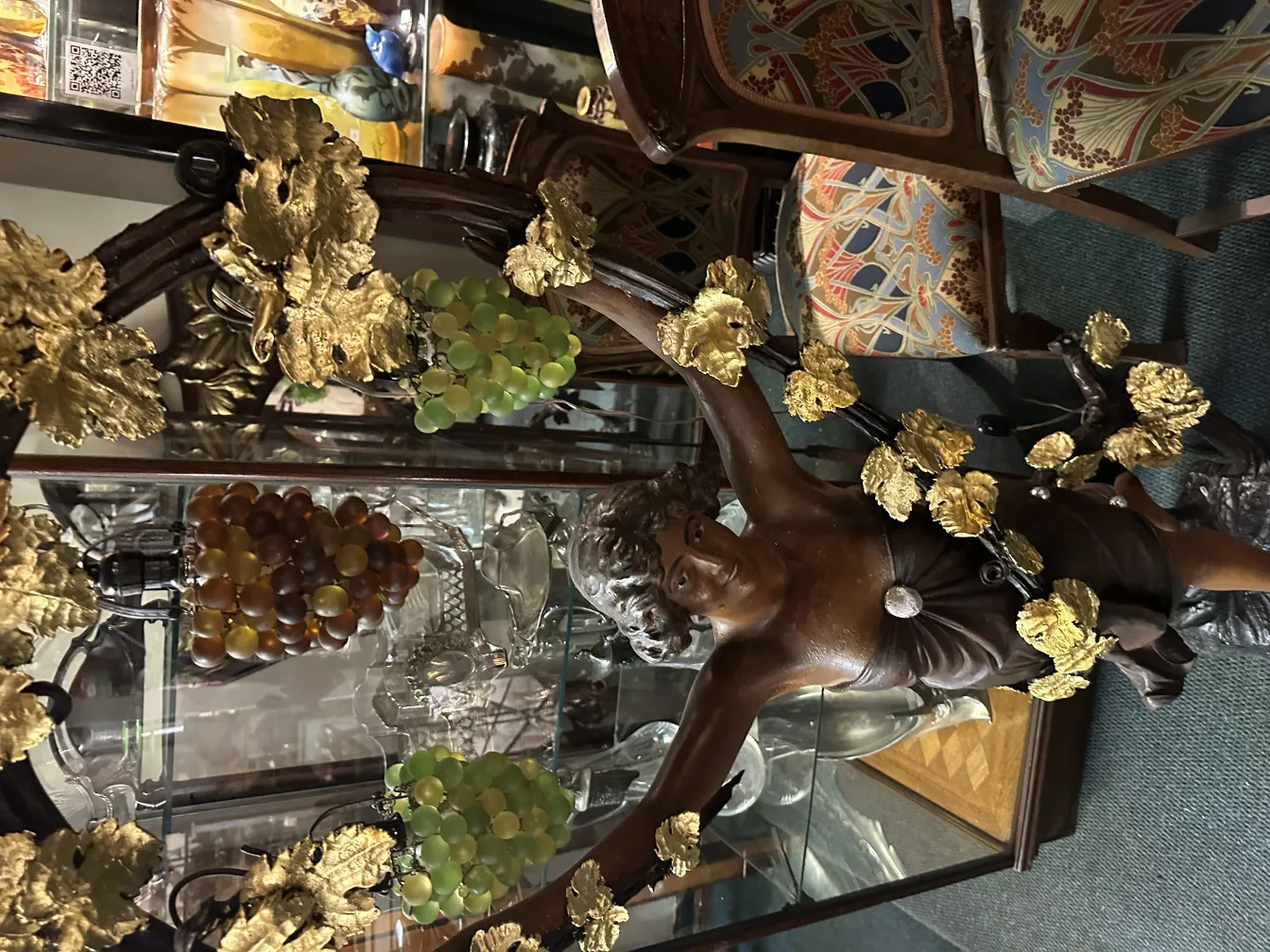 scultura antica di un uomo circondato da foglie e uva dorate