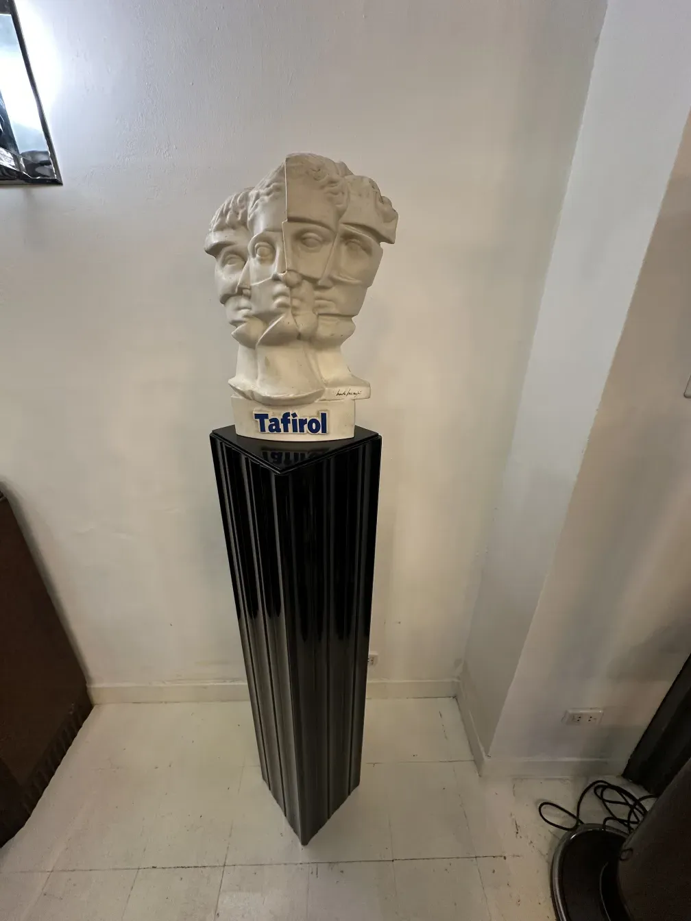 Columna antigua con escultura en la parte superior y base decorativa en un entorno moderno