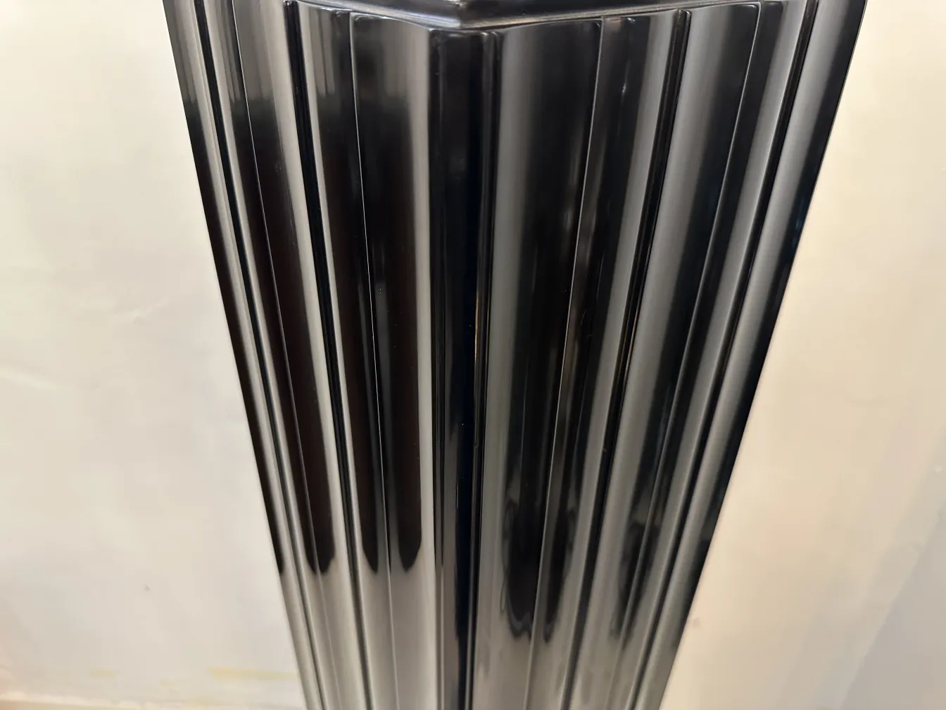 Antique black column with modern design, beautifully carved, set against a light background.